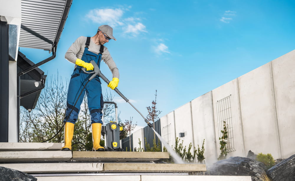 a man washing his backyard using a professional power washing machine
